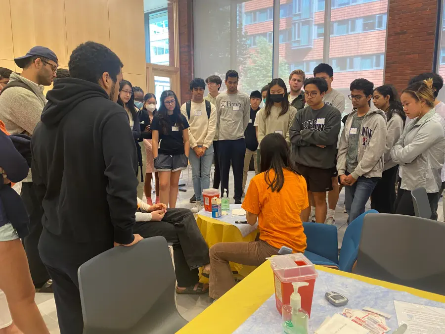 Penn students gather around a volunteer training demonstration